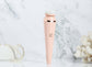 4-in-1 rechargeable facial cleansing brush in pink, on a marble background, showcasing its sleek design.