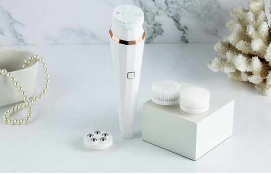 4-in-1 rechargeable facial cleansing brush with interchangeable heads and accessories on a clean marble surface.